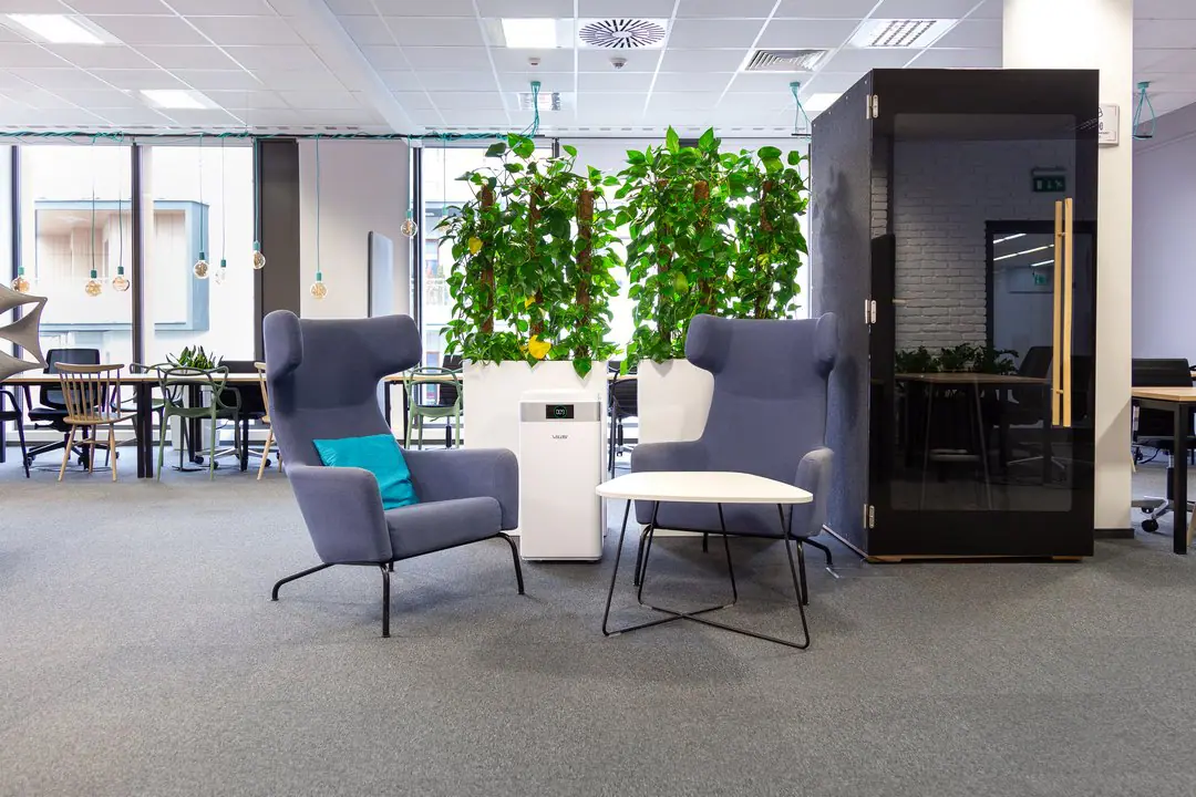 Oczyszczacz powietrza w open space z zielenią i budkami akustycznymi